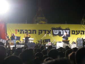 protest - The stage and part of the harbor in the back. The sign says "The people demand social justice" - Haifa