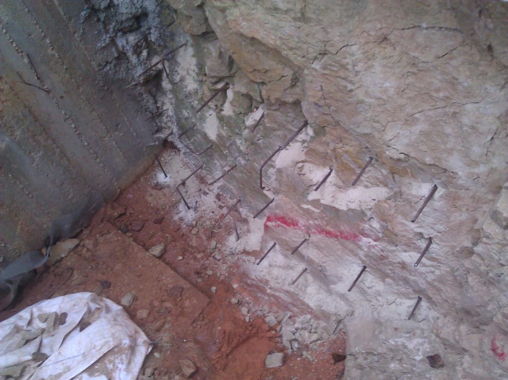 Reinforcement bars inserted into the rock to hold it and connect the rock and the concrete. - drain pipe