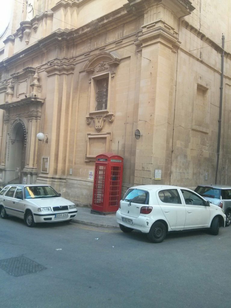 A red telephone booth in the street of Valletta