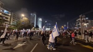 Ayalon Highway full of protestors. Above is Azrieli center light with the slogan "we are one nation"